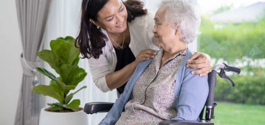 The doctor happily talks with the aged woman who has ulcer wounds.