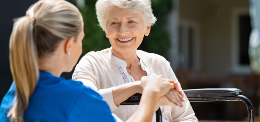 The aged woman happily talks with the nurse after treating her chronic wound.