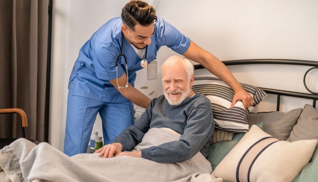 The caregiver helps the elderly patient change position to avoid pressure sores.