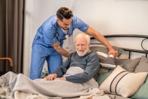 The caregiver helps the elderly patient change position to avoid pressure sores.