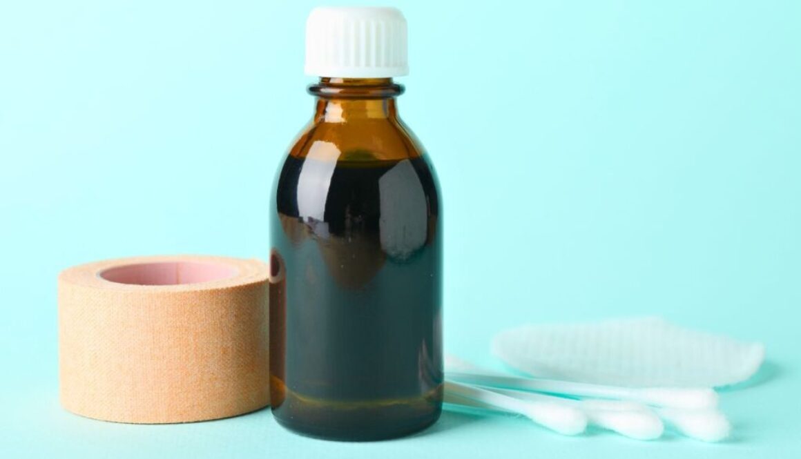 A bottle of topical iodine for wounds with cotton applicator and medical tape.