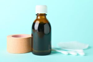 A bottle of topical iodine for wounds with cotton applicator and medical tape.
