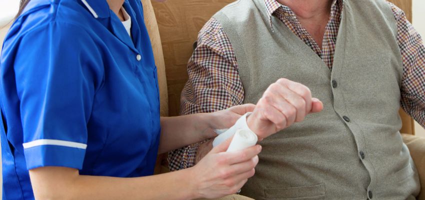 The caregiver checks to see if the wound is healing.